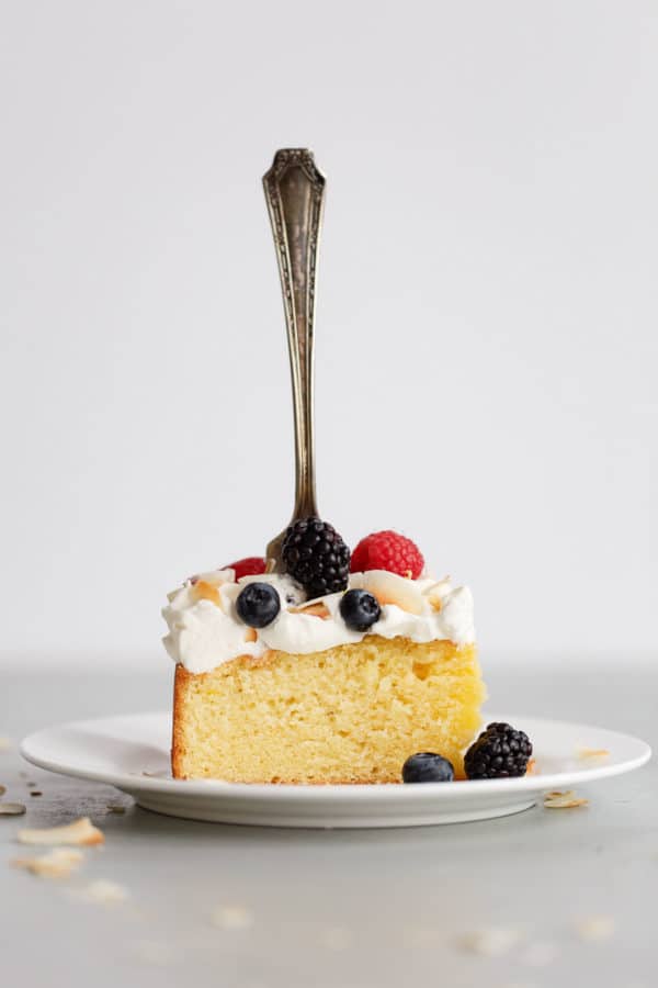 Slice of Lemon Coconut Cake with Whipped Cream Frosting and Berries