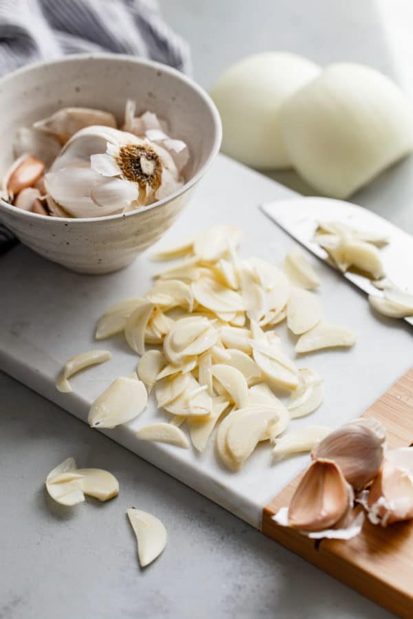 Thinly Sliced Garlic Cloves on Cutting Board