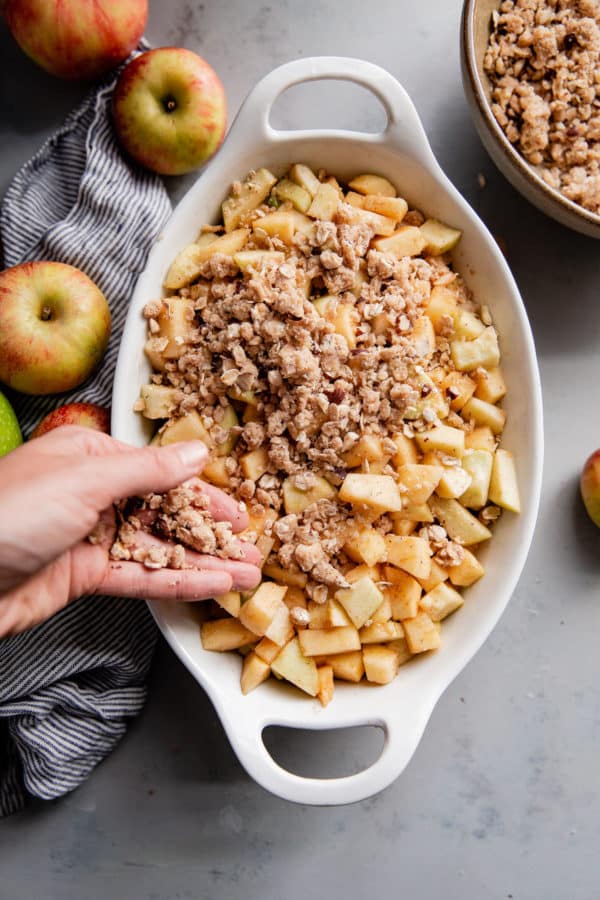 Crisp Topping Being Sprinkled on Top of Apple Crisp