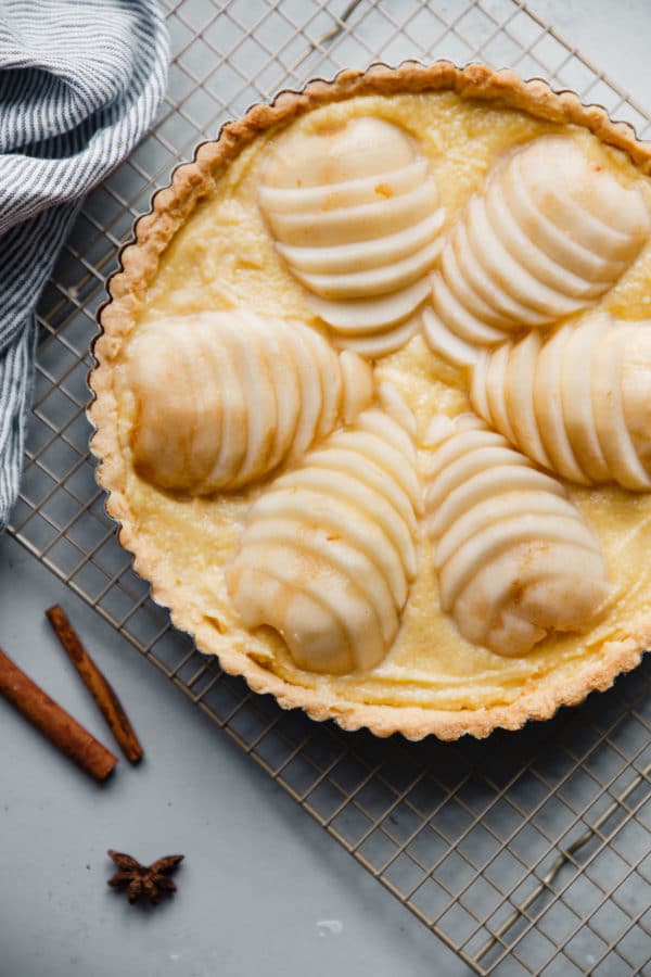 Pear Frangipane Tart - this classic French poached pear tart recipe is made with a sweet tart dough and filled with poached pears and frangipane (almond cream). This tart is delicious and is wonderful served on Thanksgiving or over the holiday season! Top with powdered sugar or apricot glaze. #tart #recipe #abeautifulplate #pear #frangipane #poached #French #dessert #pastry