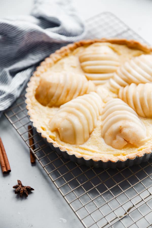 Pear Frangipane Tart - this classic French poached pear tart recipe is made with a sweet tart dough and filled with poached pears and frangipane (almond cream). This tart is delicious and is wonderful served on Thanksgiving or over the holiday season! Top with powdered sugar or apricot glaze. #tart #recipe #abeautifulplate #pear #frangipane #poached #French #dessert #pastry