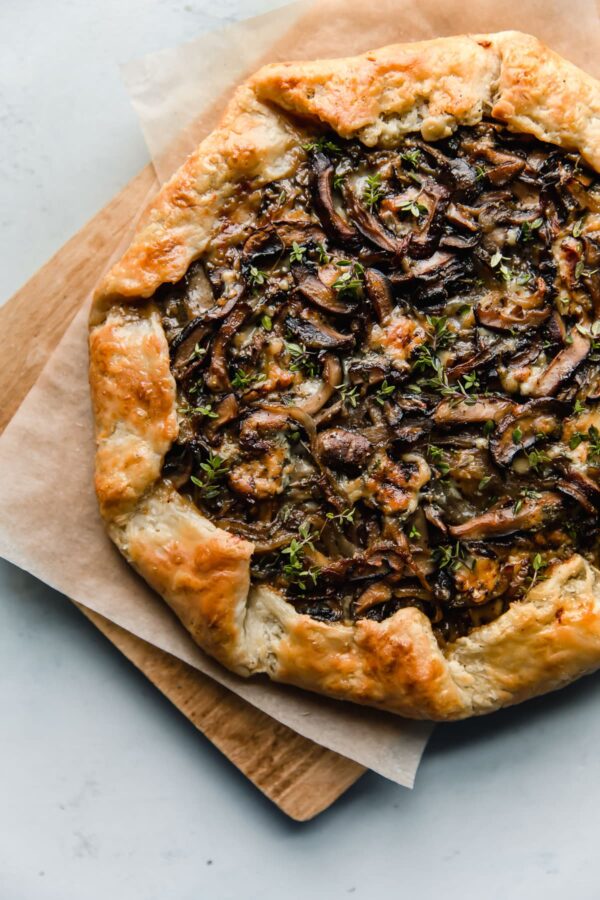 Mushroom Galette - rustic and flavorful, this cremini and shiitake mushroom galette is filled with sharp blue cheese and wrapped in a flaky sour cream pastry dough. This rustic mushroom tart is great for entertaining! #galette #mushroom #tart #cremini #shiitake #recipe #abeautifulplate Mushroom Galette with Blue Cheese on Cutting Board