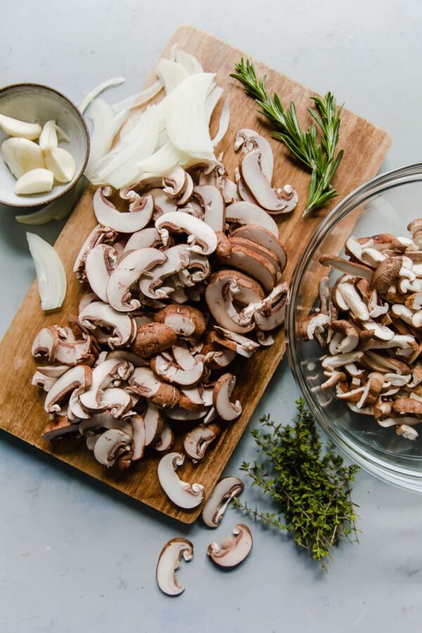 Sliced Mushrooms and Onion on Cutting Board with Herbs