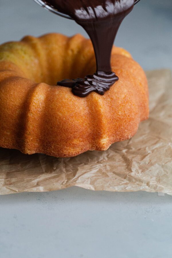 Chocolate Glaze Being Poured on Orange Bundt Cake