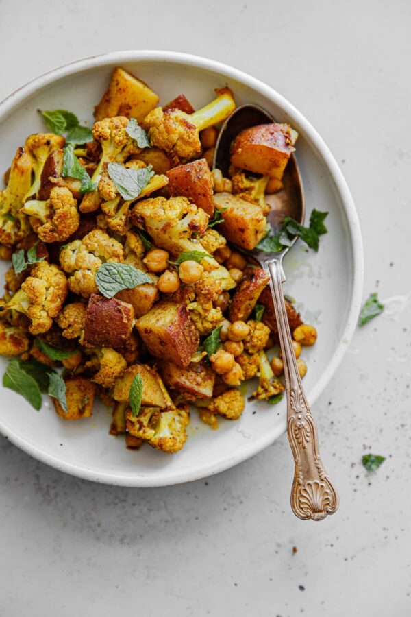 Sheet Pan Roasted Cauliflower Chickpea Curry on Plater with Serving Spoon