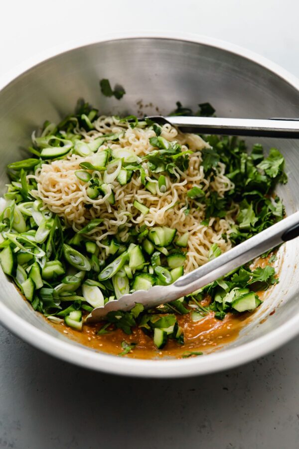 Spicy Peanut Noodles Being Mixed with Tongs