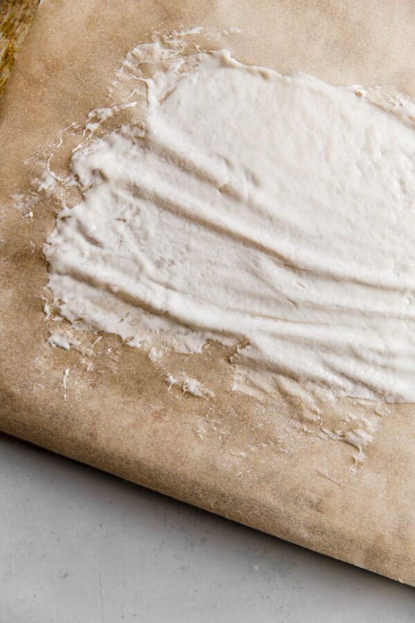 thinly spread sourdough starter on parchment paper