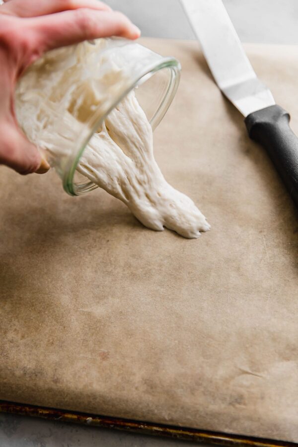 pouring sourdough starter onto parchment paper for drying