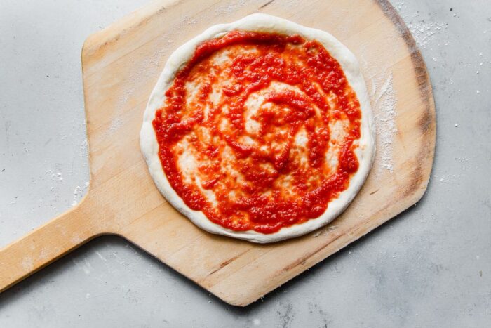 Homemade Pizza Sauce Spread on Pizza Dough on a Pizza Peel