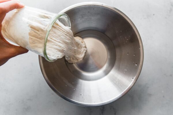 Pouring Sourdough Starter into Water for Pizza Dough