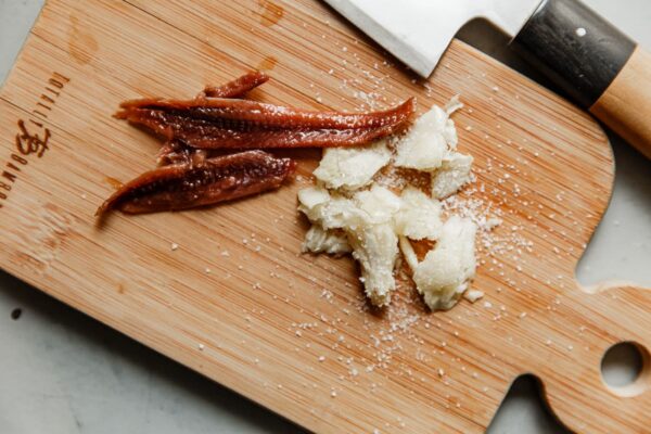 Anchovy Fillets and Smashed Garlic on Cutting Board